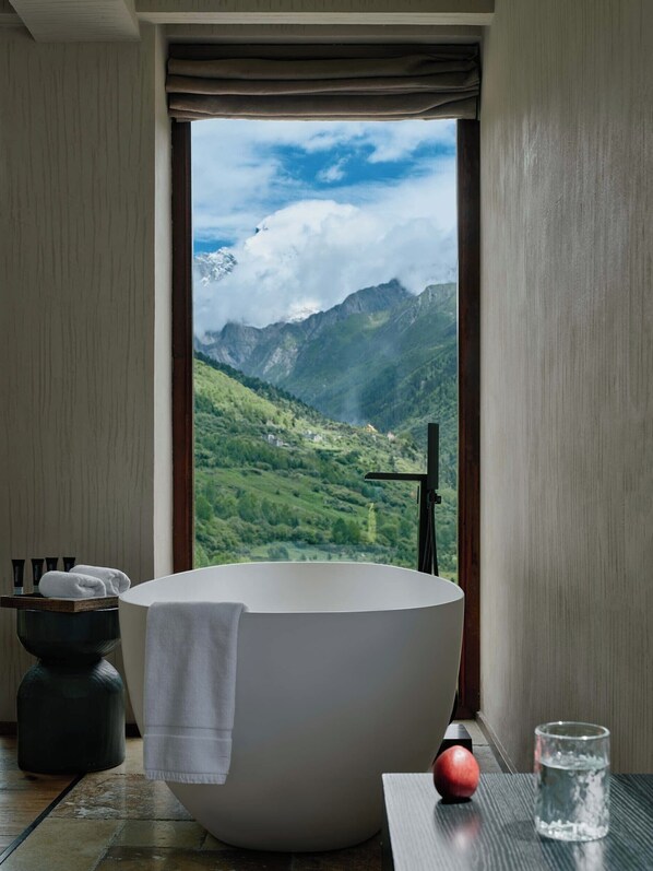 A modern bathroom with a freestanding bathtub, a glass of water, and toiletries on a shelf. - DAINN Mt Siguniang (Ngawa Autonomous Prefecture)