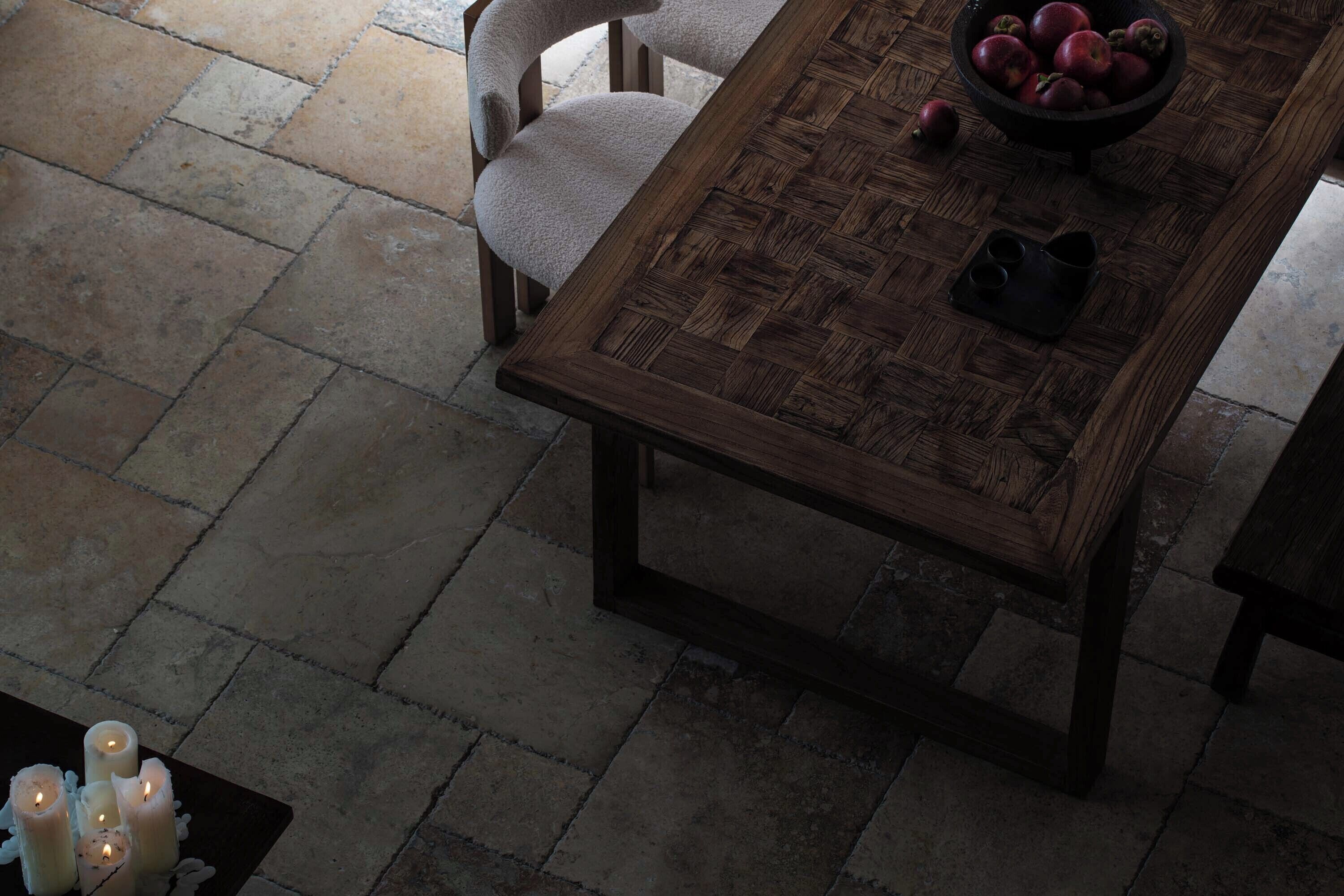 Una mesa de comedor de madera con un diseño tejido, rodeada de sillas y un bol de manzanas sobre la mesa.
