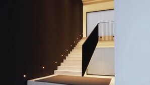 Un escalier moderne avec une rampe noire et un mur de couleur claire.