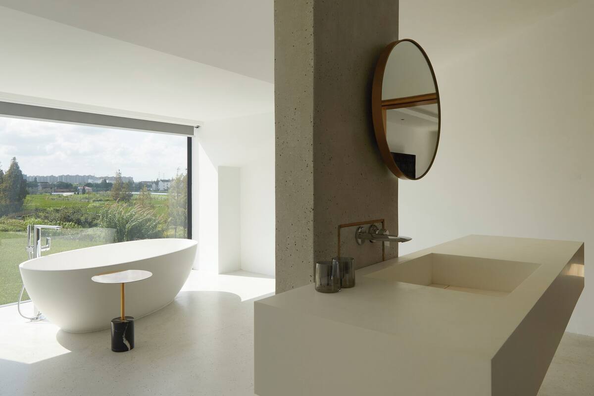 Ein modernes Badezimmer mit einem großen Fenster, einer freistehenden Badewanne und einem schlichten Waschtischdesign.