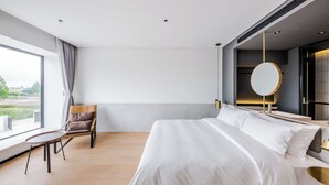 Une chambre d’hôtel moderne, dotée d’un grand lit, d’une chaise, d’une table et offrant une vue sur l’extérieur.