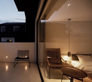 A modern bedroom with a bed, two chairs, a small table, and a nightstand. - The House Of Mo (Shanghai)
