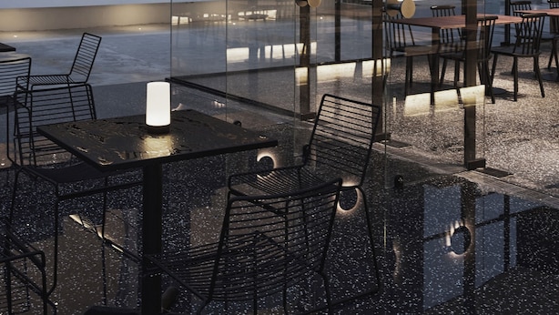 Un espace de restauration extérieur moderne, doté de cloisons en verre, de tables et de chaises.