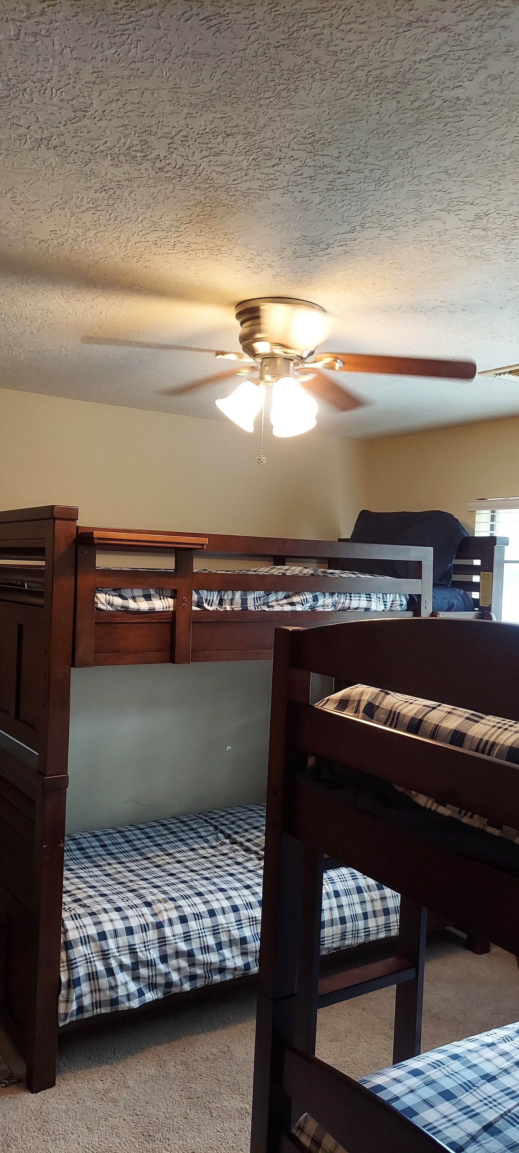 A bunk bed room with a ceiling fan and a light fixture.