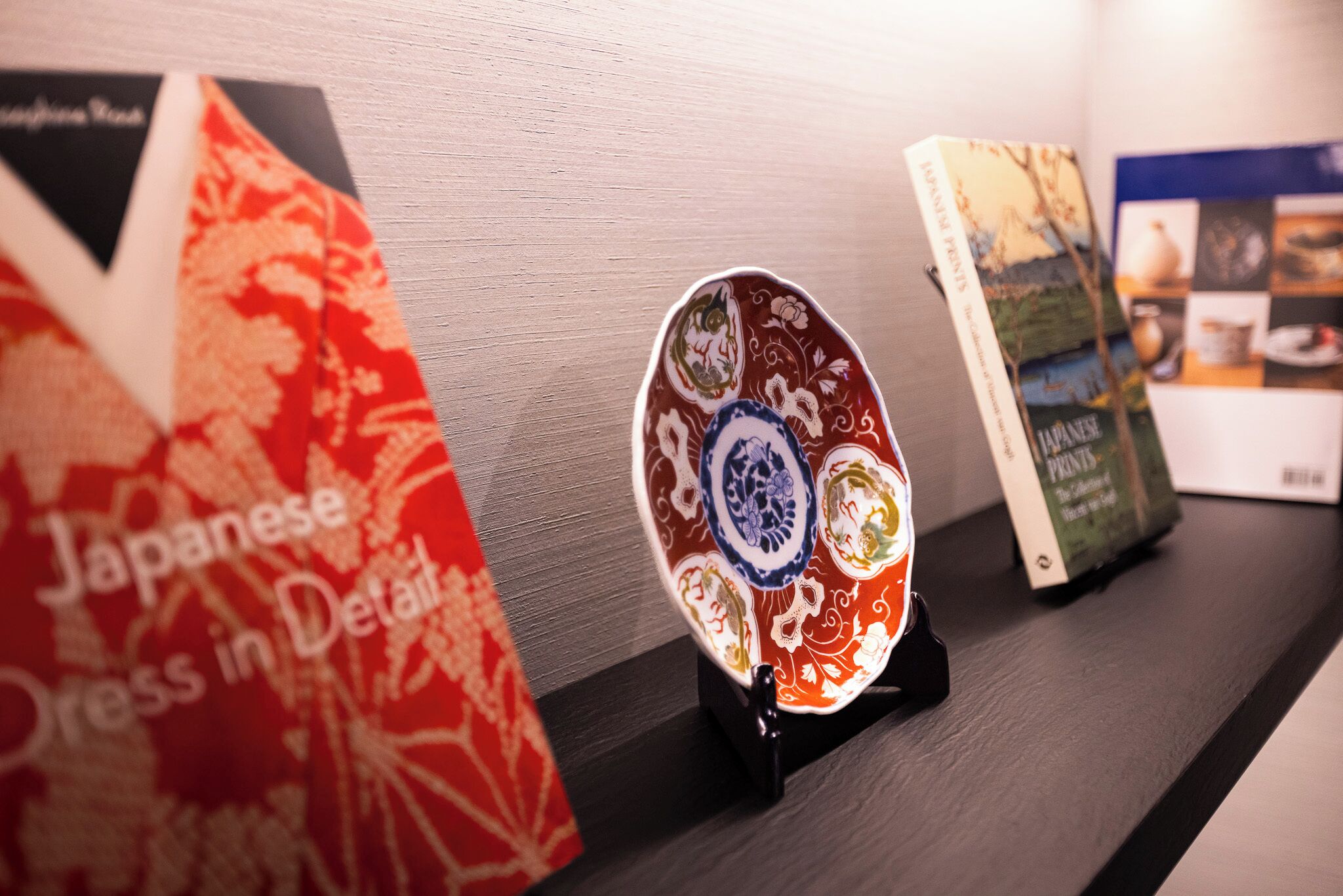 Una estantería con libros y un plato decorativo.