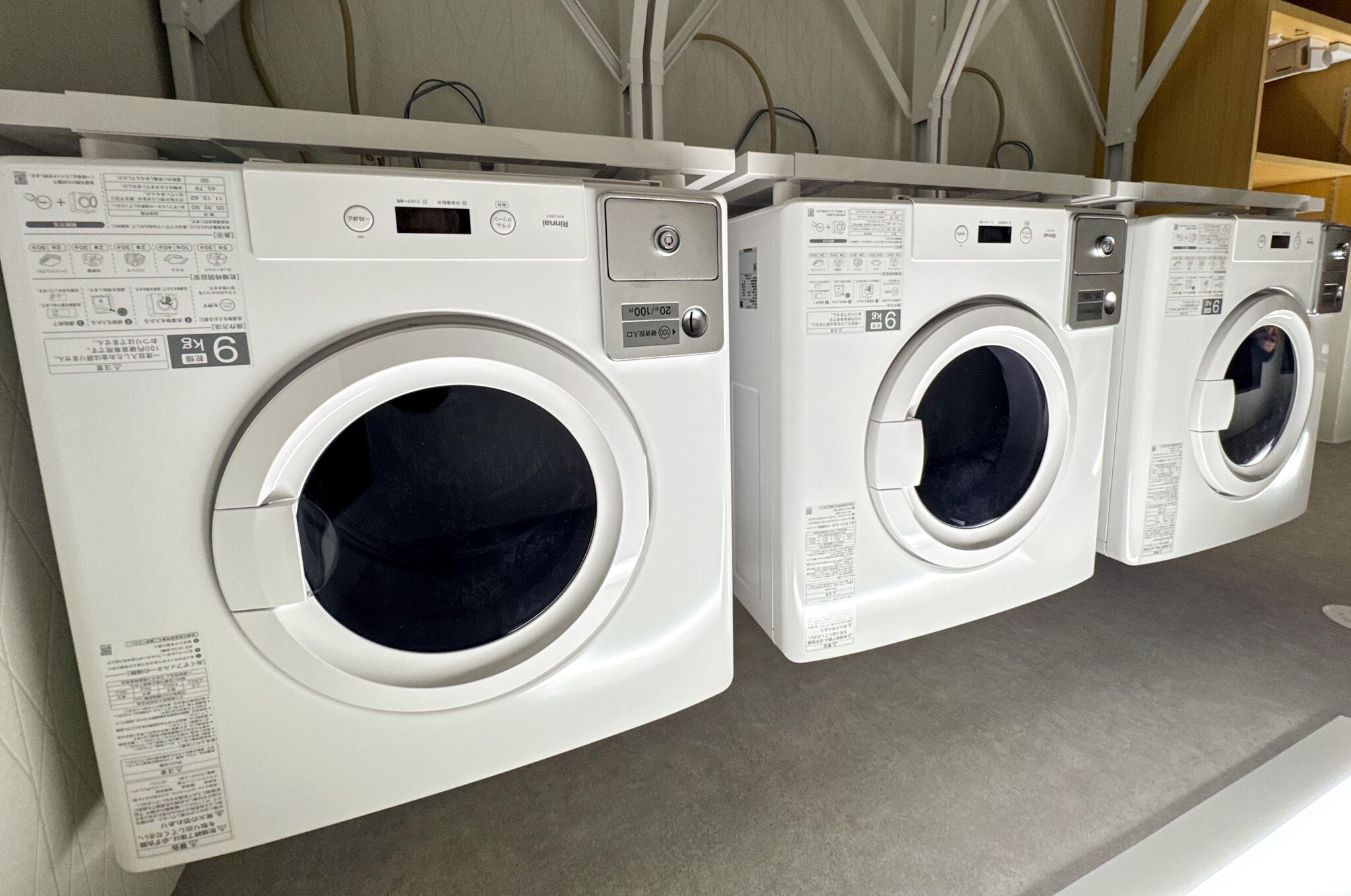 A row of white front-loading washing machines in a commercial setting.