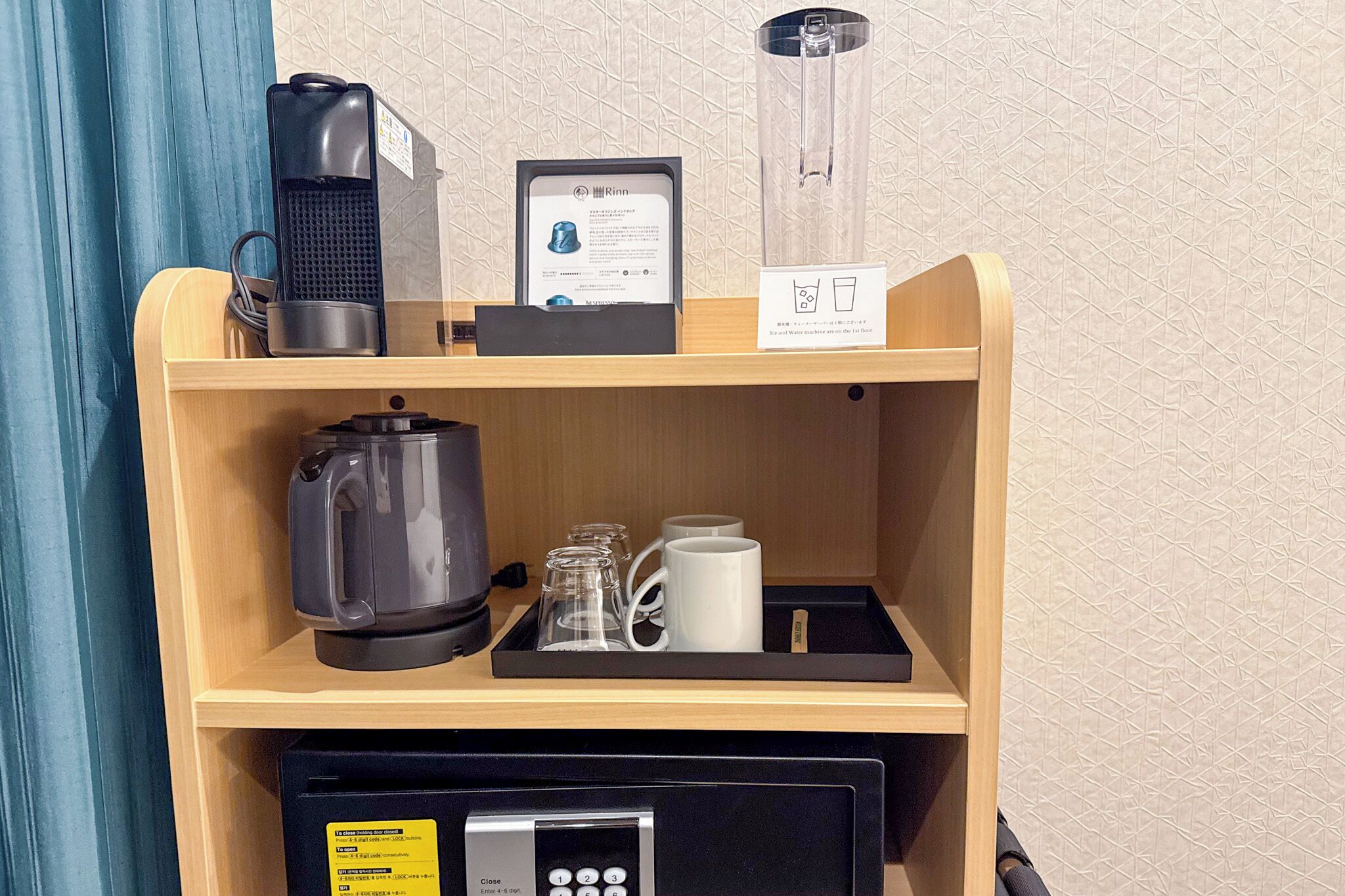 Un coin café comprenant une machine à café, une bouilloire et une autre machine à café, le tout placé sur une étagère en bois.