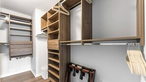A walk-in closet with wooden shelving, a hanging rod, and a shoe rack.
