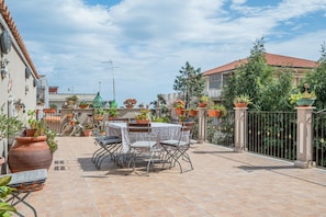 A patio with a table and chairs, surrounded by potted plants and a bicycle.