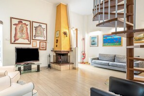 A modern living room with a fireplace, a sofa, a television, and artwork on the walls.