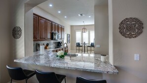 A kitchen with a marble countertop, wooden cabinets, and a dining area with chairs. - Luxury 3 bedroom in gated Grayhawk community (Scottsdale)