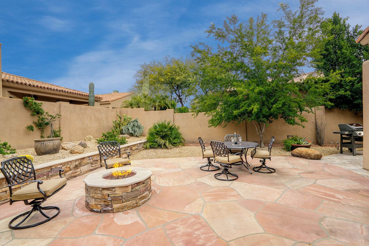 An outdoor patio with stone flooring, a fire pit, and outdoor furniture.
