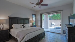 A bedroom with a large bed, a ceiling fan, a nightstand, a dresser, and a sliding glass door leading to a patio. - Luxury 3 bedroom in gated Grayhawk community (Scottsdale)