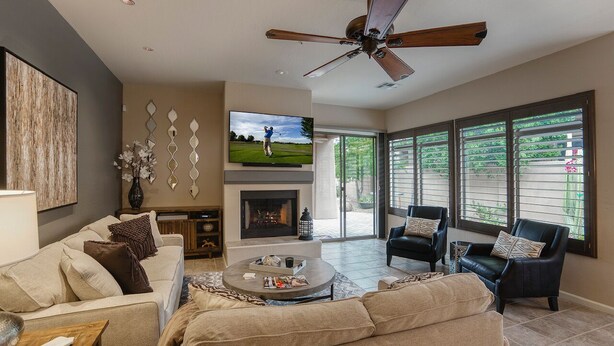 A spacious living room with a fireplace, comfortable seating, and large windows offering a view of the outdoors. - Luxury 3 bedroom in gated Grayhawk community (Scottsdale)