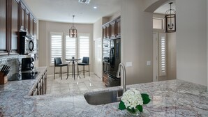 A kitchen with a marble countertop, stainless steel appliances, and a dining area with a table and chairs. - Luxury 3 bedroom in gated Grayhawk community (Scottsdale)