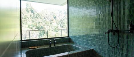 A bathroom with a large window, a bathtub, and a shower.