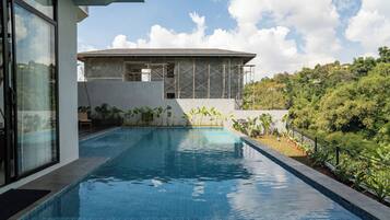 Piscina con vista a un edificio en construcción y follaje circundante.