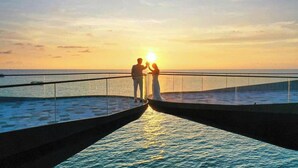 A sunset view from a bridge over water, with two people facing each other. - 2 Bedrooms Apartment In Sunset Town (Phu Quoc)