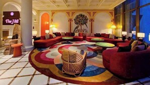 A lobby with red sofas, a patterned carpet, and a large tree painting. - 2 Bedrooms Apartment In Sunset Town (Phu Quoc)