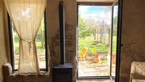 A rustic room with a wood-burning stove, a window with a view of the outdoors, and a chair by the window. - "Hühnerstudio - Schlamau19" Studio with Shared Terrace and Shared Garden  (Wiesenburg/Mark)