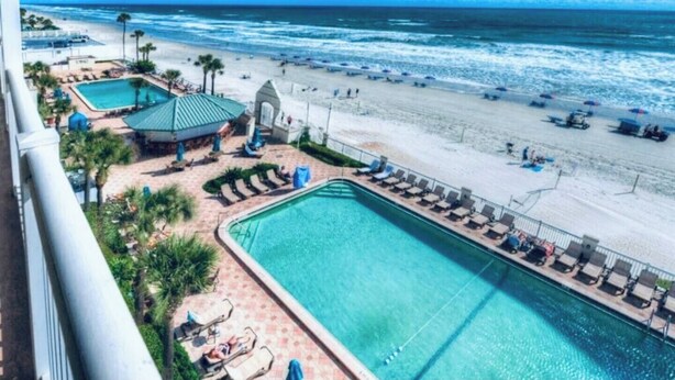 Zona de piscina con vista a la playa y al océano.