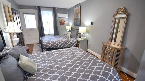 A hotel room with two beds, a dresser, a mirror, and a window with curtains.