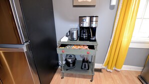 A kitchen with a stainless steel refrigerator, a coffee maker, and a blender on a small table.