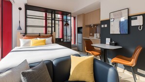 Una habitación de hotel moderna con cama, escritorio y kitchenette.