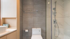 Un baño moderno con inodoro, cabina de ducha de vidrio y pared revestida de mármol.