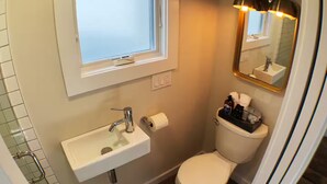 A bathroom with a white sink, a toilet, and a window above the sink. - The Wiedler - Charming Tiny Home - AC, WiFi in the heart of the action! (Portland)
