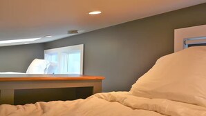 A bedroom with a bed, a bedside table, a window, and a ceiling light. - The Wiedler - Charming Tiny Home - AC, WiFi in the heart of the action! (Portland)