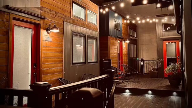 A cozy, well-lit indoor space with wooden paneling, a seating area, and string lights. - The Wiedler - Charming Tiny Home - AC, WiFi in the heart of the action! (Portland)