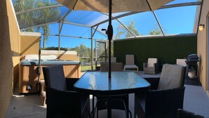 Une terrasse extérieure dotée d’une véranda en verre, d’un jacuzzi et de différents espaces pour s’asseoir.