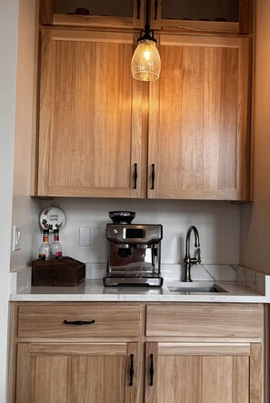 Enjoy cooking in this well-equipped kitchen with a coffee maker, ample counter space, and a convenient hanging light fixture.