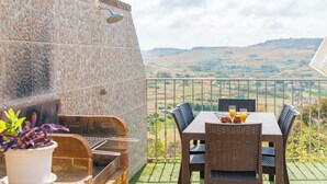 A patio with a stone wall, a grill, and a table with chairs and drinks. - Ta Dora Sleeps 6 with Private Pool (Xaghra)