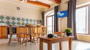 A cozy dining area with wooden furniture, a table with a teapot, and a view of the sea through large windows. - Ta Dora Sleeps 6 with Private Pool (Xaghra)
