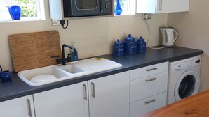 Een keuken met een spoelbak, magnetron en wasmachine.