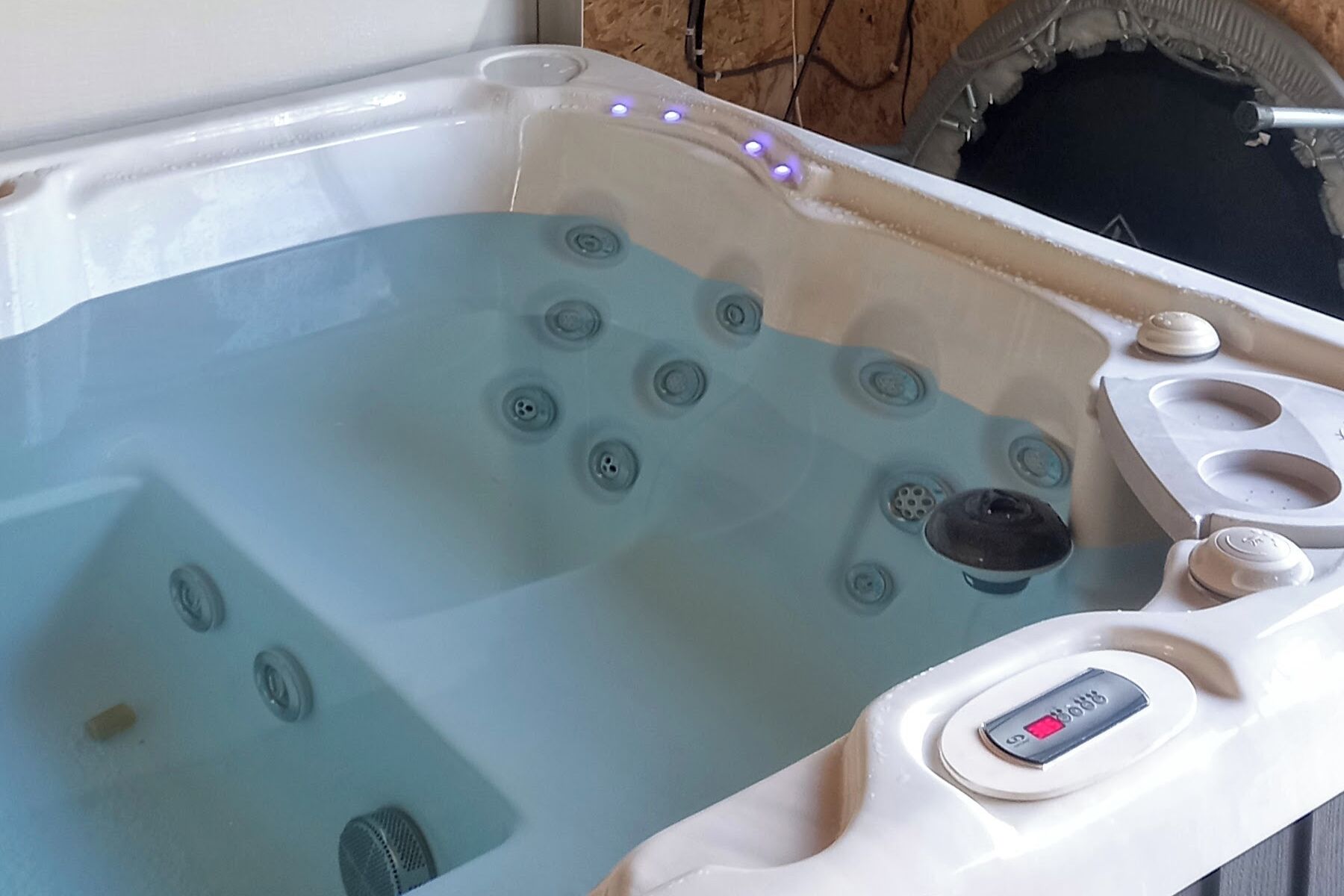 Ett bubbelbad med flera massagemunstycken, en kontrollpanel med en digital display och en stenmur i bakgrunden.