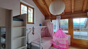Ein gemütliches Schlafzimmer mit einem Etagenbett, einem rosa Spielzelt und großen Fenstern mit Blick nach draußen.