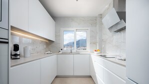 A modern kitchen with white cabinets, a built-in oven, and a window with a city view. - Estepona Beachfront Promenade by Libehomes (Estepona)