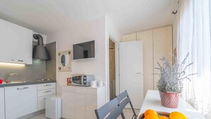 A compact kitchen with a microwave, sink, and cabinets. There's a TV mounted above the microwave, and a potted plant on the windowsill. - Rena Bianca Mono - 5 mins from the beach, WiFi, AC (Olbia)