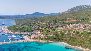 An aerial view of a coastal marina with boats, a residential area, and a mountainous backdrop. - Rena Bianca Mono - 5 mins from the beach, WiFi, AC (Olbia)