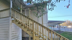 Una escalera de madera que lleva a una casa con porche cubierto.