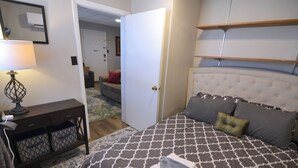 Un dormitorio con cama, mesita de noche, lámpara y mueble de almacenamiento.