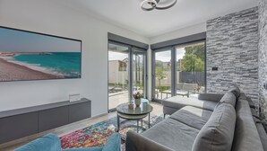 A modern living room with a large flat-screen TV, grey sofa, and a colorful rug. - Villa Gigi with private Pool, Višnjan, Croatia (Višnjan)