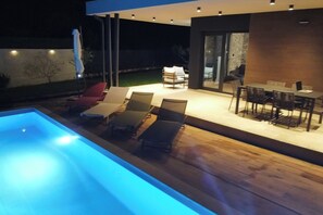 An outdoor pool area with lounge chairs and a dining table.
