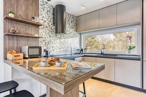 A modern kitchen with a central island, built-in appliances, and a window with a view of trees. - Villa Gigi with private Pool, Višnjan, Croatia (Višnjan)