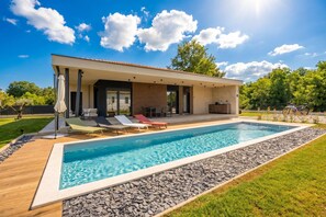 Une maison moderne dotĂ©e dâune piscine, dâun espace salon extĂ©rieur et dâune terrasse.