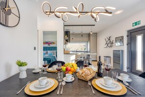 A modern dining area with a dark wooden table set for a meal, a fruit bowl, and a wine bottle. - Villa Gigi with private Pool, Višnjan, Croatia (Višnjan)