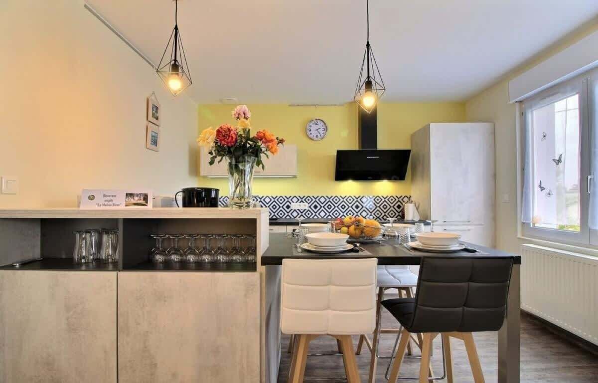 Una cocina moderna con una isla central, sillas blancas y una mesa de comedor.